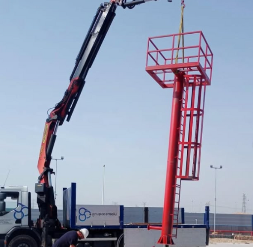 Grúa en operación para el montaje de estructuras metálicas industriales de gran altura. Instalación profesional de elementos prefabricados.