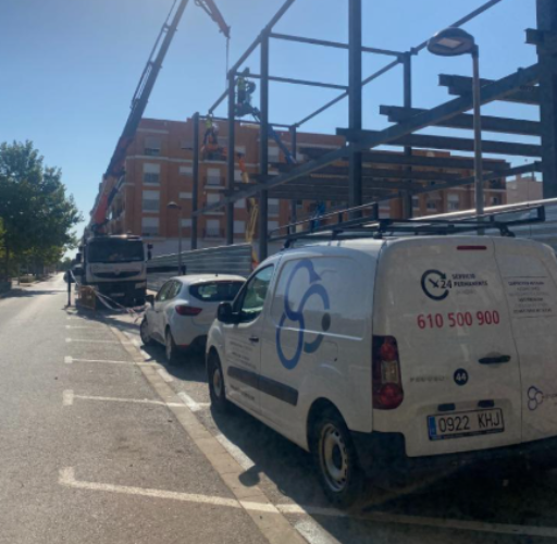 Estructuras metálicas industriales en fase de instalación en obra, con equipo logístico y grúa para el montaje.