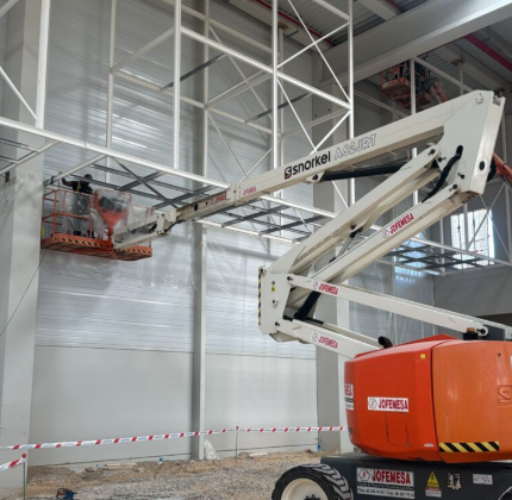 Instalación de estructura metálica en altura con plataforma elevadora en nave industrial — equipo de Cemalu realizando montaje seguro y preciso de perfiles de acero.